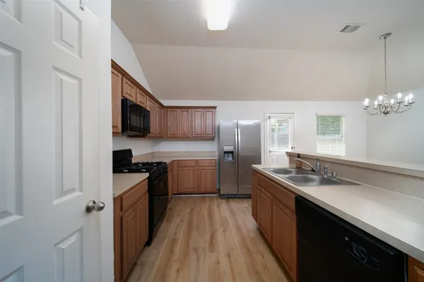 a kitchen with stainless steel appliances granite countertop a sink a stove a refrigerator cabinets a dining table and chairs