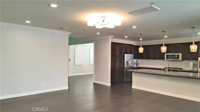 a kitchen with a sink dishwasher and a refrigerator with wooden floor