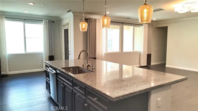 a view of a kitchen with stainless steel appliances granite countertop a sink dishwasher a stove and a dining table with wooden floor