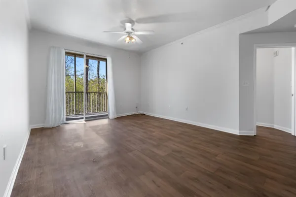 a view of an empty room with wooden floor and a window
