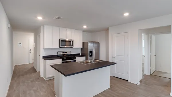a kitchen with kitchen island granite countertop stainless steel appliances a refrigerator a stove a sink a microwave and cabinets