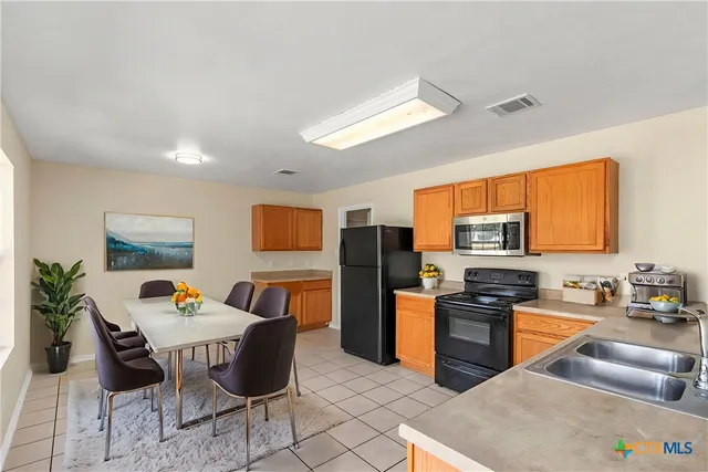 a kitchen with stainless steel appliances granite countertop a stove a sink a dining table and chairs