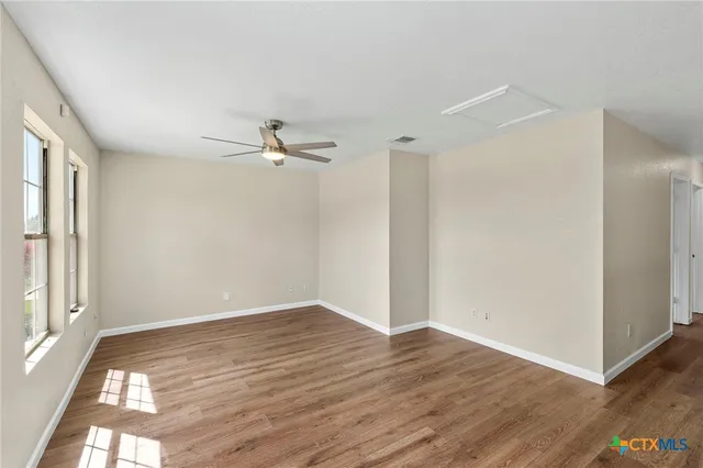 a view of a room with wooden floor and a ceiling fan