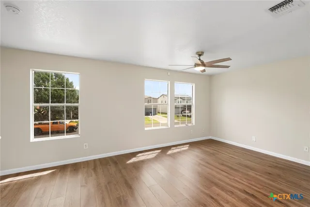 an empty room with wooden floor and windows