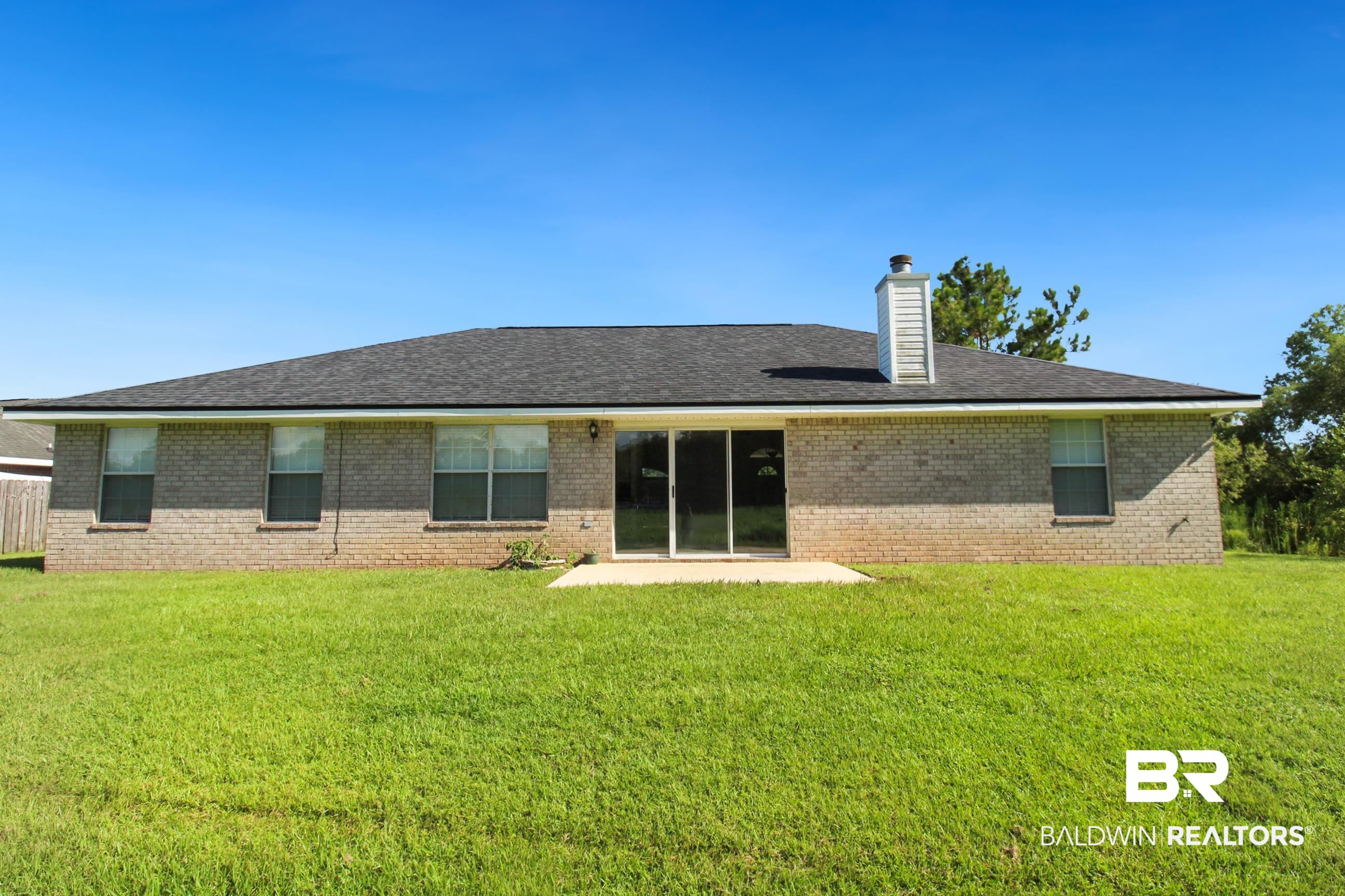 14750 Pawnee Court Foley, AL 36535 - Photo 32 of 34 Rear view of property with a chimney, brick siding, a lawn, and a patio area