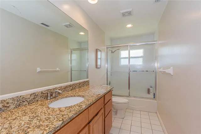 a bathroom with a granite countertop sink a toilet and shower