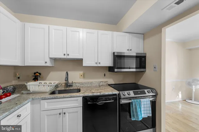 a kitchen with granite countertop white cabinets and black appliances