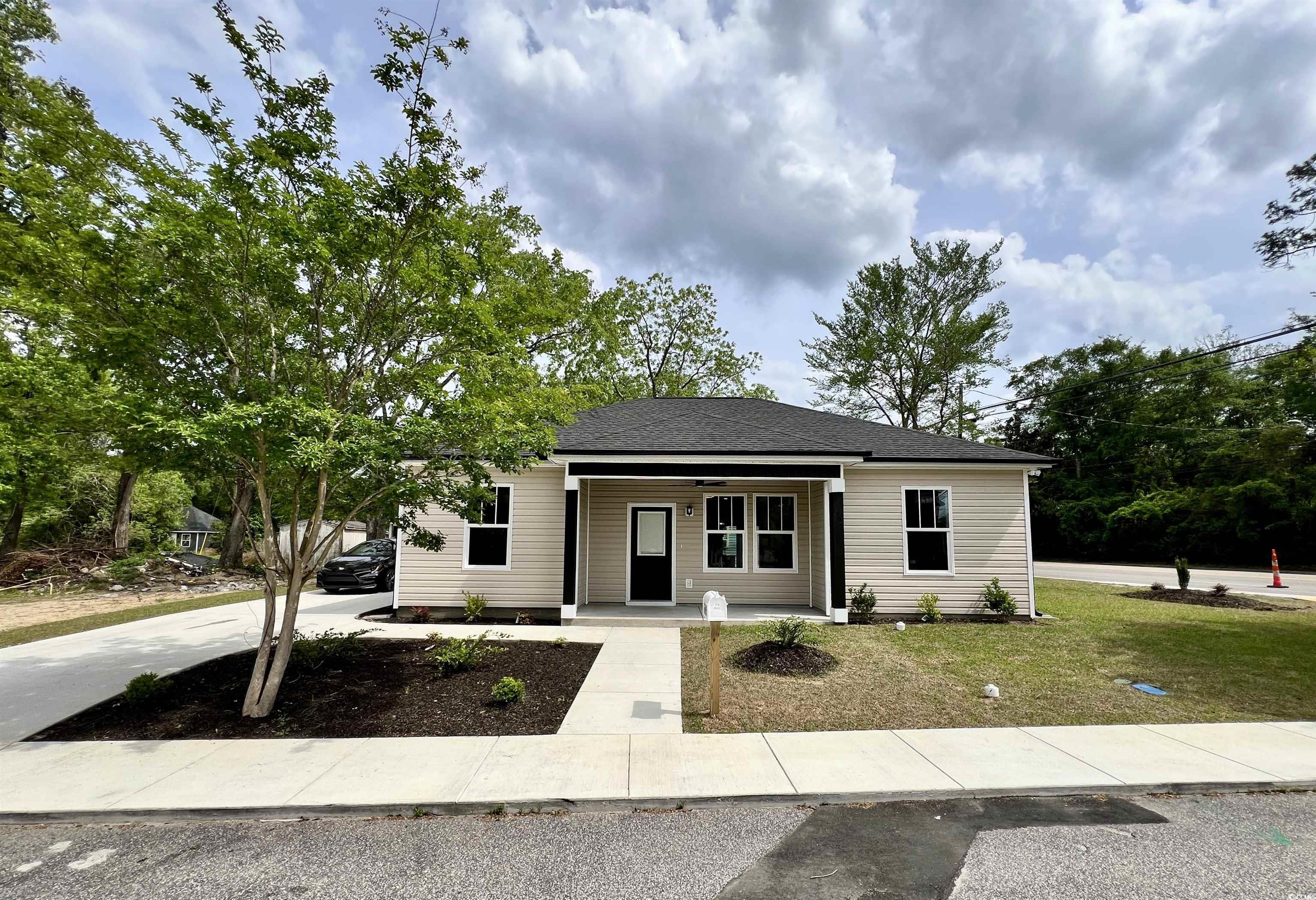 View of front of property featuring a porch, a front lawn, a shingled roof, and driveway