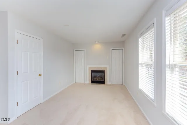 a view of an empty room with window and fire place