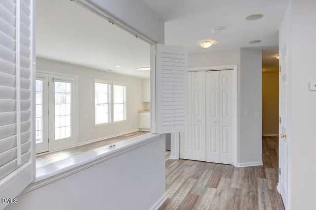 a view of an empty room with a window and wooden floor