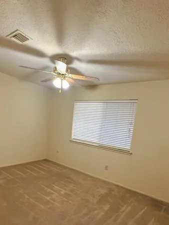 an empty room with a ceiling fan and window