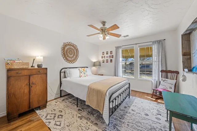 a bedroom with a bed and dresser with wooden floor
