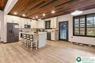 a kitchen with stainless steel appliances granite countertop a stove top oven a refrigerator a oven with a dining table and chairs with wooden floor