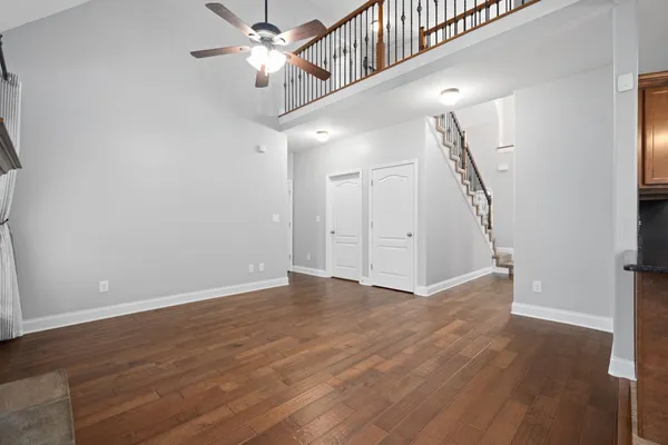 a view of an empty room with wooden floor and a ceiling fan