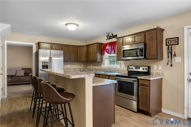 a kitchen with stainless steel appliances granite countertop a stove top oven a sink dishwasher a dining table and chairs with wooden floor