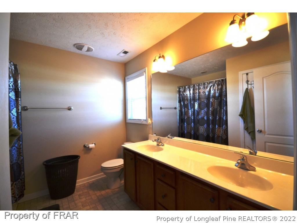 645 Cape Fear Road Raeford, NC 28376 - Photo 20 of 24 a bathroom with a double vanity sink toilet and mirror