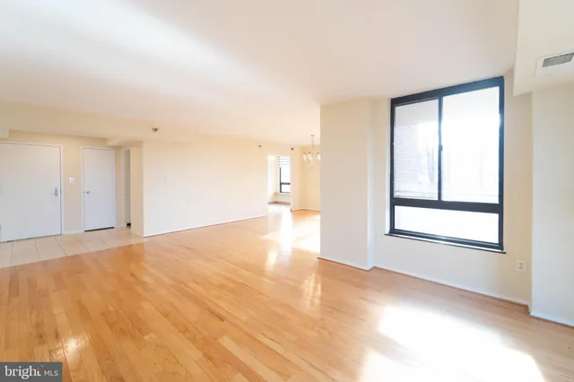 a view of an empty room with wooden floor and a window