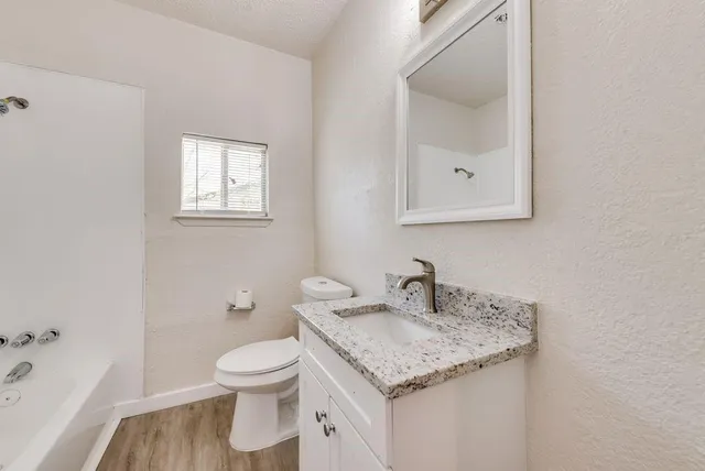 a bathroom with a granite countertop sink a toilet and a bathtub