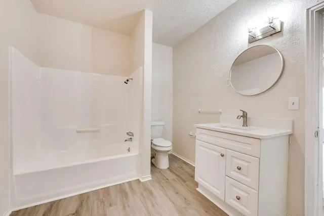 a spacious bathroom with a toilet a sink a mirror and a bathtub