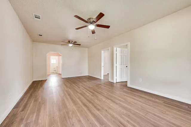 an empty room with wooden floor and a ceiling fan