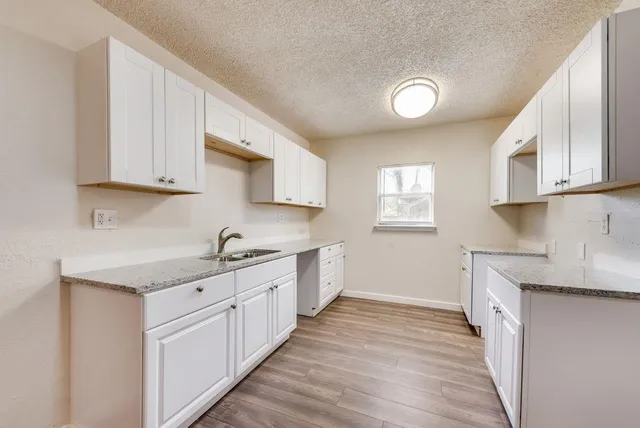 a kitchen with granite countertop a sink and cabinets