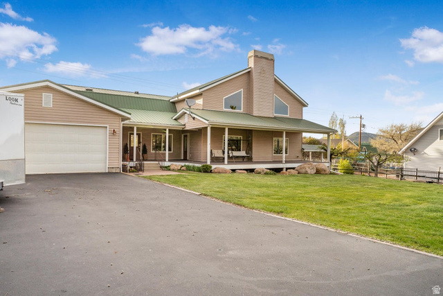 48 South Sage Road Pine Valley, UT 84781 - Photo 56 of 61 Exterior featuring a green metal roof, light-colored siding, a covered porch, an attached garage, and a paved driveway