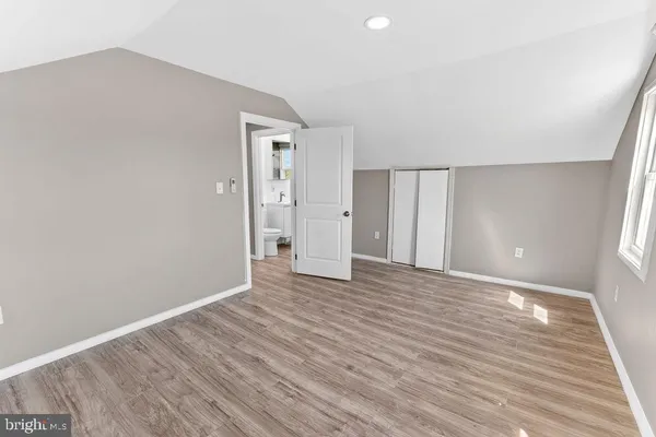 a view of an empty room with wooden floor and closet
