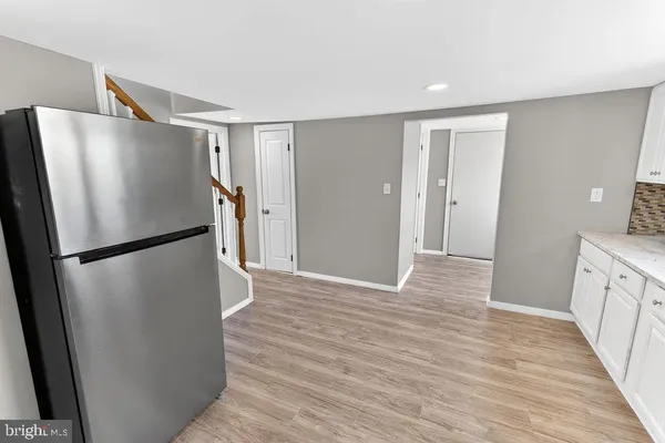 a view of a kitchen with refrigerator and wooden floor