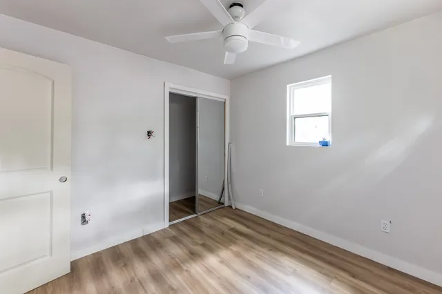 a view of empty room with wooden floor and fan
