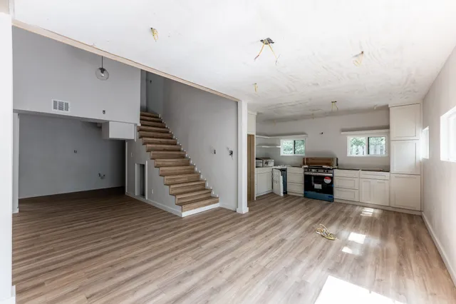 a view of a kitchen with wooden floor electronic appliances and stairs