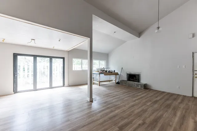 a view of an empty room with a window and wooden floor
