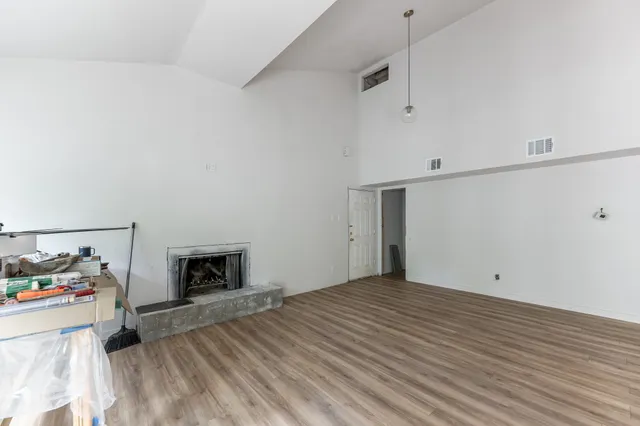 a view of empty room with fireplace and wooden floor