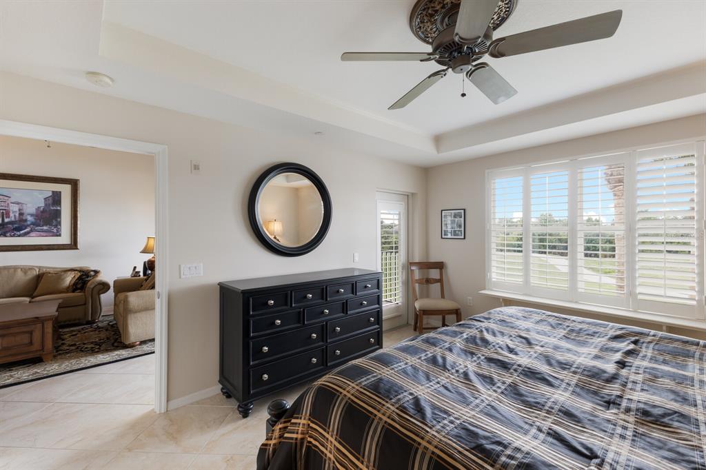 7179 Boca Grove Place, Unit 202 Lakewood Ranch, FL 34202 - Photo 21 of 46 a bedroom with a bed a dresser and a chandelier