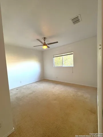 an empty room with windows and chandelier fan