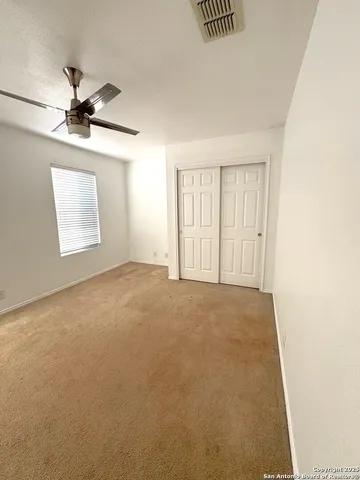 an empty room with windows and fan