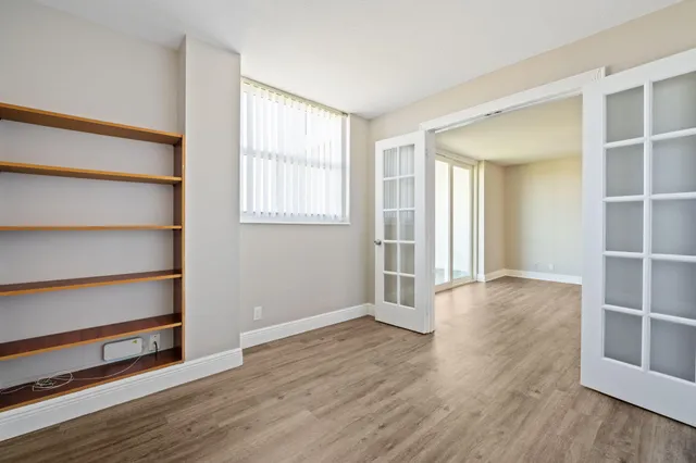 a view of an empty room with wooden floor and windows