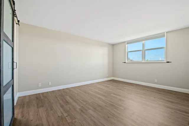 a view of an empty room with wooden floor and a window