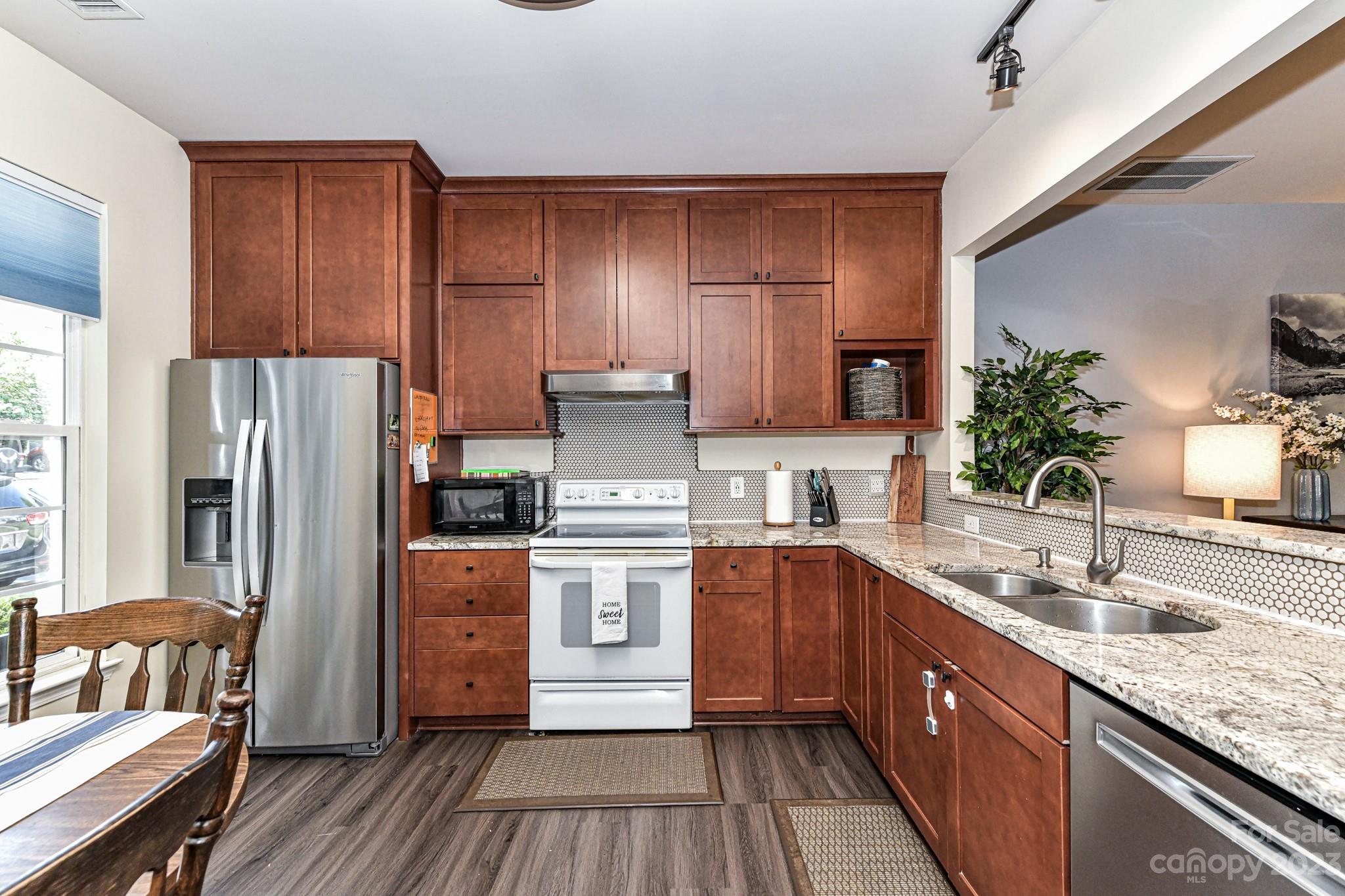 6991 Rothchild Drive Charlotte, NC 28270 - Photo 4 of 37 a kitchen with stainless steel appliances granite countertop a refrigerator a sink dishwasher a stove with wooden cabinets and floor
