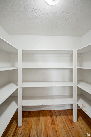 2058 California Avenue, Unit 2 Provo, UT 84606 - Photo 17 of 32 U-shaped shelving system featuring multiple shelves, white painted finish, wood-finish flooring, and a ceiling-mounted light fixture