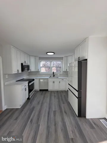 a large kitchen with a center island wooden floor stainless steel appliances and cabinets