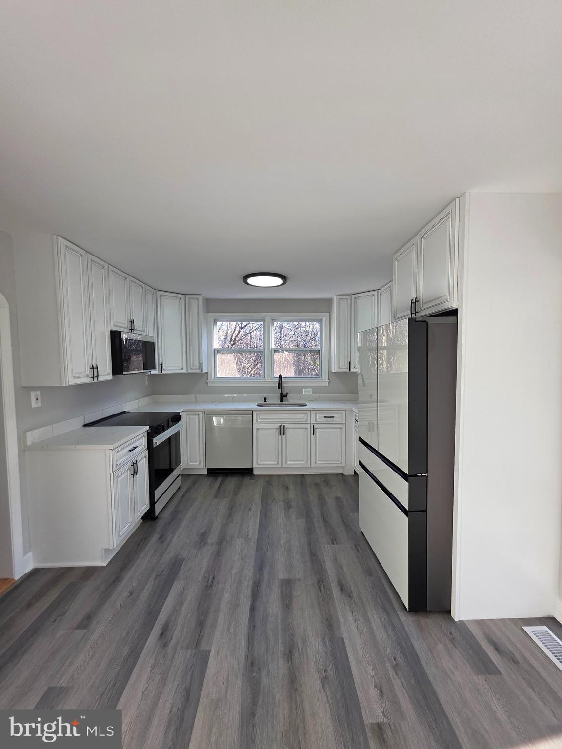 a large kitchen with a center island wooden floor stainless steel appliances and cabinets