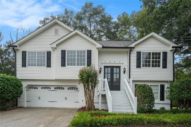 a view of a white house with a small yard and large tree