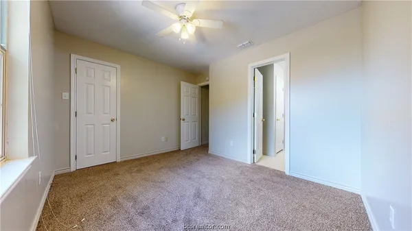 an empty room with a ceiling fan and a bathroom