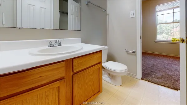 a bathroom with a granite countertop sink toilet and a mirror