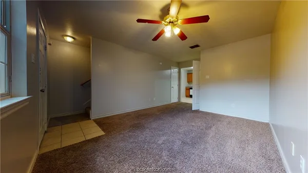 en empty room with an entryway and chandelier fan