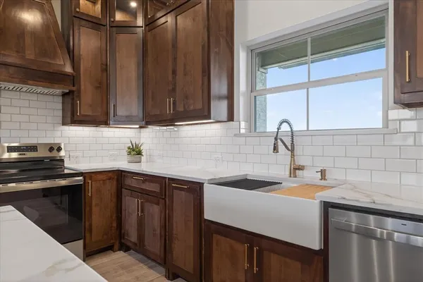 a kitchen with stainless steel appliances granite countertop a sink a stove and cabinets