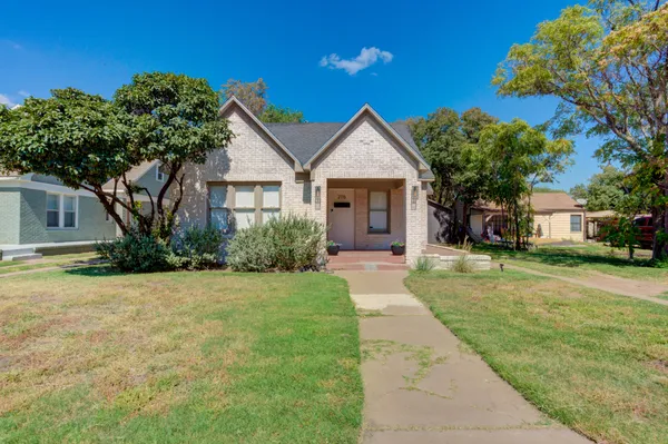 a front view of a house with a yard and trees