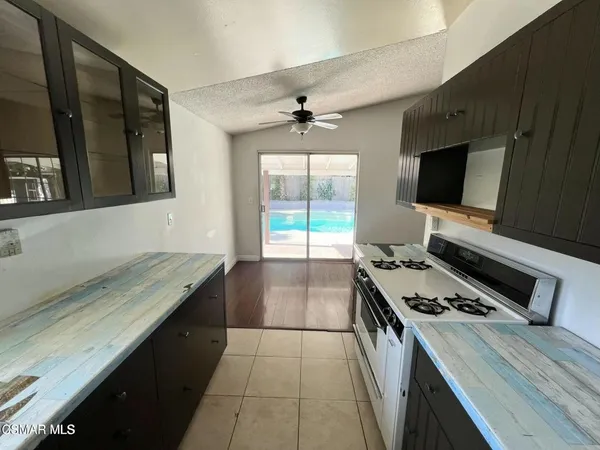 a kitchen with a stove and a flat screen tv