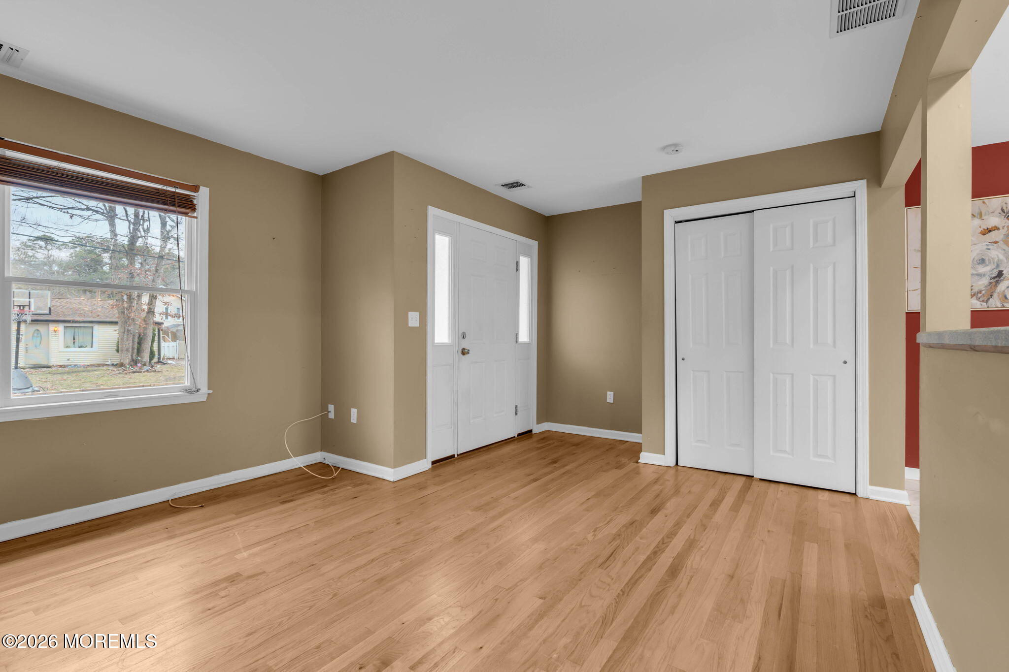 a view of an empty room with wooden floor and a window