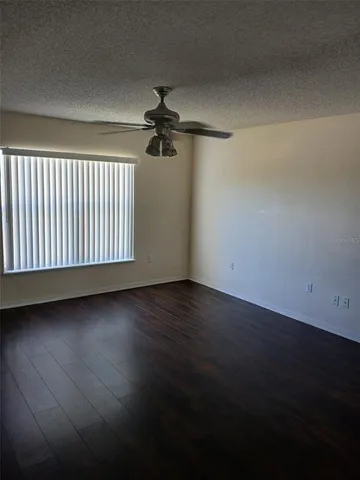 an empty room with wooden floor fan and windows